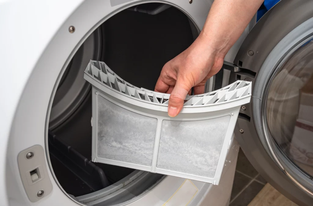man cleaning lint trap in dryer for maintenance